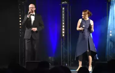 widzimy pana śpiewającego na scenie oraz panią trzymającą mikrofon w dłoni