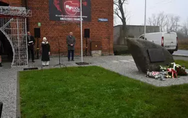 widzimy dziewczynkę m&oacute;wiącą do mikrofonu oraz kilka os&oacute;b stojących obok 