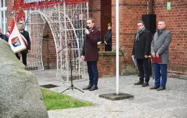widzimy pana m&oacute;wiącego do mikrofonu oraz dw&oacute;ch pan&oacute;w stojących obok 