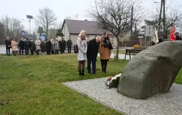 widzimy trzy osoby stojące przed pomnikiem