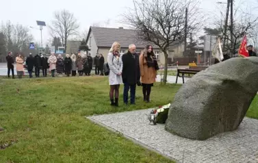 widzimy trzy osoby stojące przed pomnikiem
