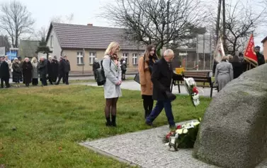 widzimy pana kładącego bukiet kwiat&oacute;w pod pomnik