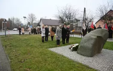 widzimy trzy osoby stojące przed pomnikiem