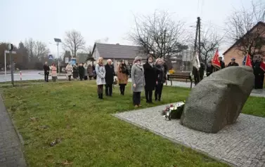 widzimy trzy osoby stojące przed pomnikiem
