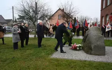 widzimy pana kładącego na pomnik bukiet kwiat&oacute;w