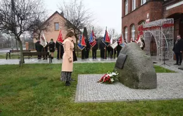 widzimy dwie osoby stojące przed pomnikem