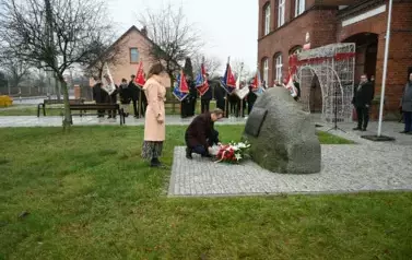 widzimy pana kładącego kwiaty pod pomnikiem