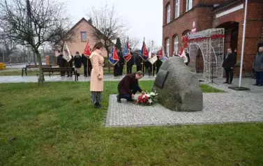 widzimy pana kładącego kwiaty pod pomnikiem