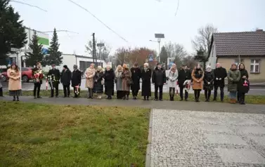 widzimy dużą liczbę os&oacute;b oraz kilka os&oacute;b z kwiatami w dłoniach