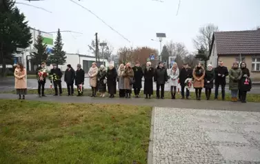 widzimy dużą liczbę os&oacute;b oraz kilka os&oacute;b z kwiatami w dłoniach