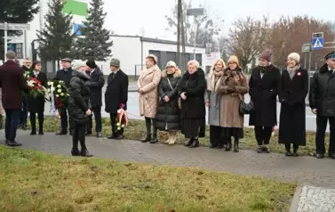 widzimy kilka os&oacute;b stojących przed pomnikiem