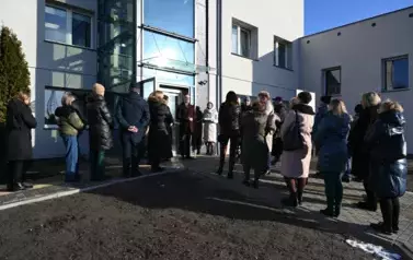 widzimy liczną grupę os&oacute;b stojącą przed windą
