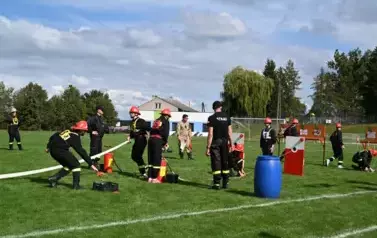 Młodzieżowa drużyna strażacka wykonuję zadanie konkurencyjne trafiając wężem z wodą do tarczy nalewowej