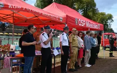 Zaproszeni goście stoją w rzędzi , jeden z nich przemawia przez mikrofon