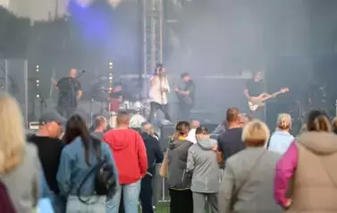 widzimy grupę os&oacute;b słuchającą koncertu a w tle zesp&oacute;ł muzyczny
