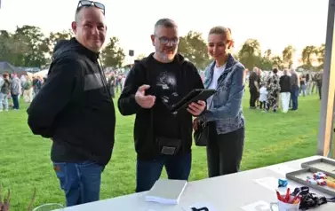 widzimy panią, pana oraz drugiego pana trzymającego tablet przy stoisku