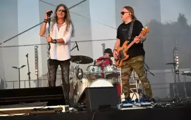 widzimy śpiewającego wokalistę, pana grającego na gitarze oraz pana grającego na perkusji
