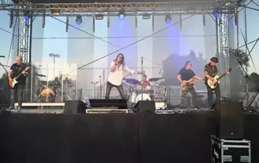 widzimy wokalistę, trzech pan&oacute;w grających na gitarze oraz pana grającego na perkusji