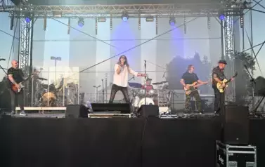 widzimy wokalistę, trzech pan&oacute;w grających na gitarze oraz pana grającego na perkusji