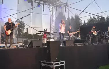 widzimy wokalistę, trzech pan&oacute;w grających na gitarze oraz pana grającego na perkusji