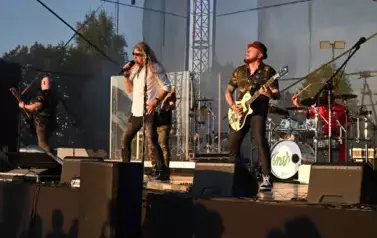 widzimy wokalistę, trzech pan&oacute;w grających na gitarze oraz pana grającego na  perkusji