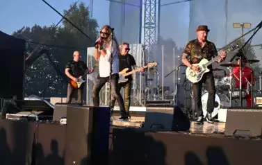 widzimy wokalistę, trzech pan&oacute;w grających na gitarze oraz pana grającego na  perkusji