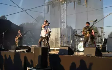 widzimy wokalistę oraz trzech pan&oacute;w grających na gitarze