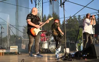 widzimy śpiewającego wokalistę oraz dw&oacute;ch pan&oacute;w grających na gitarze