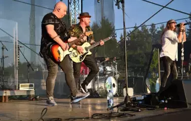 widzimy śpiewającego wokalistę oraz dw&oacute;ch pan&oacute;w grających na gitarze