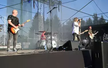 widzimy trzech pan&oacute;w grających na gitarze oraz śpiewającego wokalistę