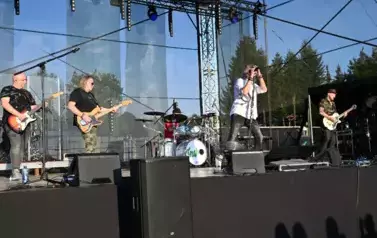 widzimy trzech pan&oacute;w grających na gitarze oraz śpiewającego wokalistę