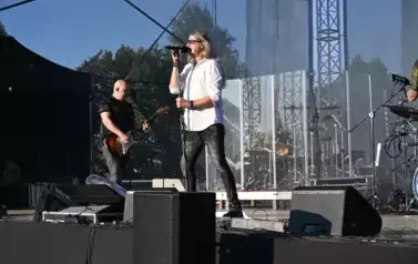 widzimy śpiewającego na scenie wokalistę oraz pana grającego na gitarze