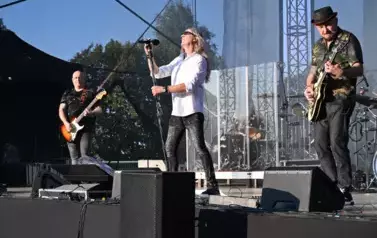 widzimy śpiewającego na scenie wokalistę oraz dw&oacute;ch pan&oacute;w grających na instrumentach