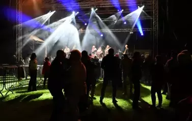 widzimy grupę os&oacute;b stojących pod sceną, na kt&oacute;rej występuje zesp&oacute;ł