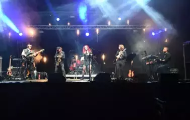widzimy panią śpiewającą oraz czterech pan&oacute;w grających na instrumentach