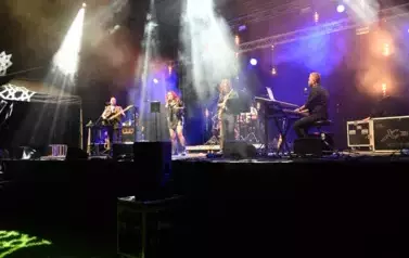 widzimy panią śpiewającą oraz czterech pan&oacute;w grających na instrumentach
