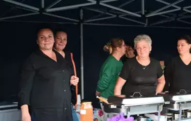 widzimy sześć os&oacute;b stojących prze stoisku 