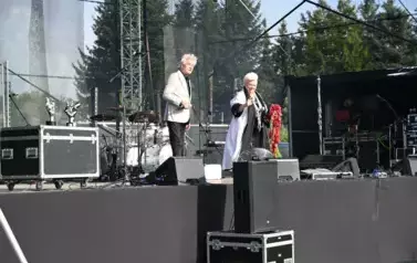 widziy pana stojącego z mikrofonem w ręce oraz panią trzymającą kwiaty w rękach