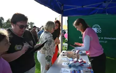 widzimy przedstawicielkę stoiska z tabletem w ręku oraz inne osoby stojące wok&oacute;ł niej