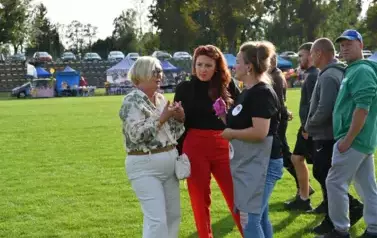 widzimy trzy panie rozmawiające ze sobą oraz inne osoby w tle 