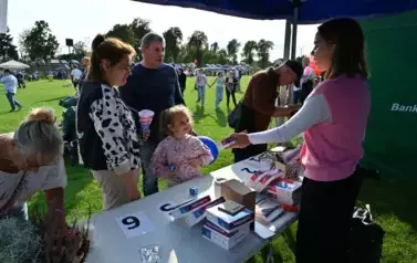 widzimy przedstawicielkę stoiska pokazującą przedmioty osobą zainteresowanym