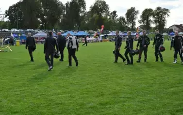 widzimy grupę pan&oacute;w ubranych na motor oraz niekt&oacute;rzy z nich trzymają kaski w dłoniach