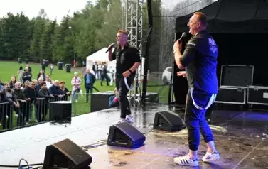 widzimy dw&oacute;ch pan&oacute;w śpiewających na scenie