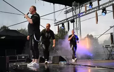 widzimy dw&oacute;ch pan&oacute;w śpiewających oraz pana idącego obok nich