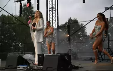 widzimy panią, kt&oacute;ra śpiewa oraz dwie panie tańczące obok niej