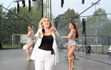 widzimy panią, kt&oacute;ra śpiewa oraz dwie panie tańczące obok niej