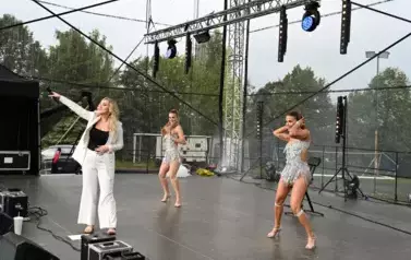 widzimy panią, kt&oacute;ra śpiewa oraz dwie panie tańczące obok niej