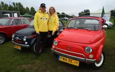 widzimy trzy antyczne samochody oraz pana i panią ubranych w bluzy z Minionk&oacute;w