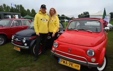 widzimy trzy antyczne samochody oraz pana i panią ubranych w bluzy z Minionk&oacute;w