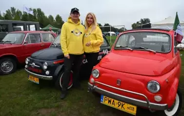 widzimy trzy antyczne samochody oraz pana i panią ubranych w bluzy z Minionk&oacute;w